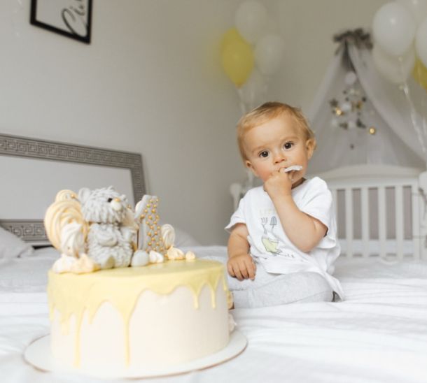 Ein Jahr altes Baby isst Geburtstagskuchen im Bett.