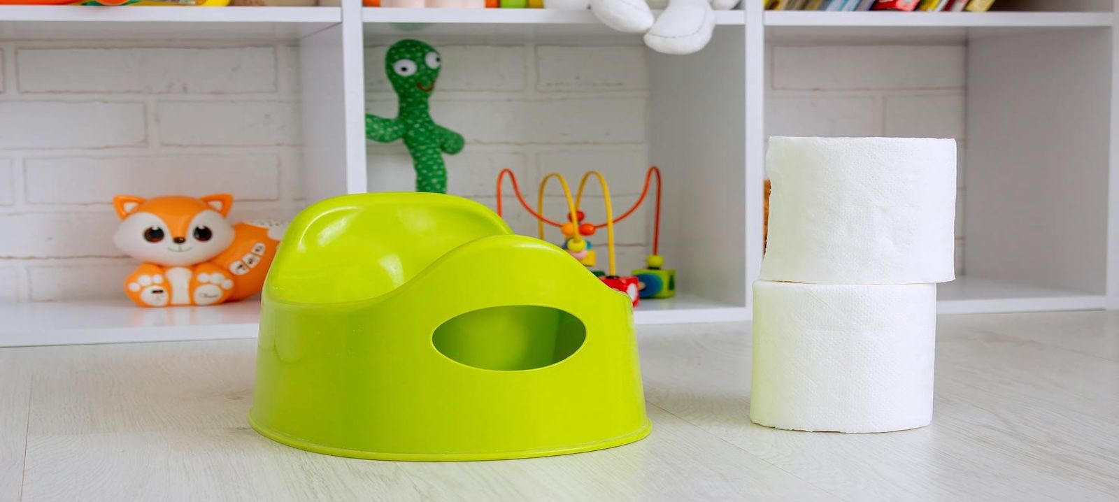 Gelbgrünes Kleinkind-Töpfchen mit drei weißen Toilettenpapierrollen daneben, vor einem Spielzeugregal mit orangem Fuchs-Spielzeug und buntem Motorikspielzeug.WiederholenClaude kann Fehler machen. Bitte überprüfen Sie die Antworten.
