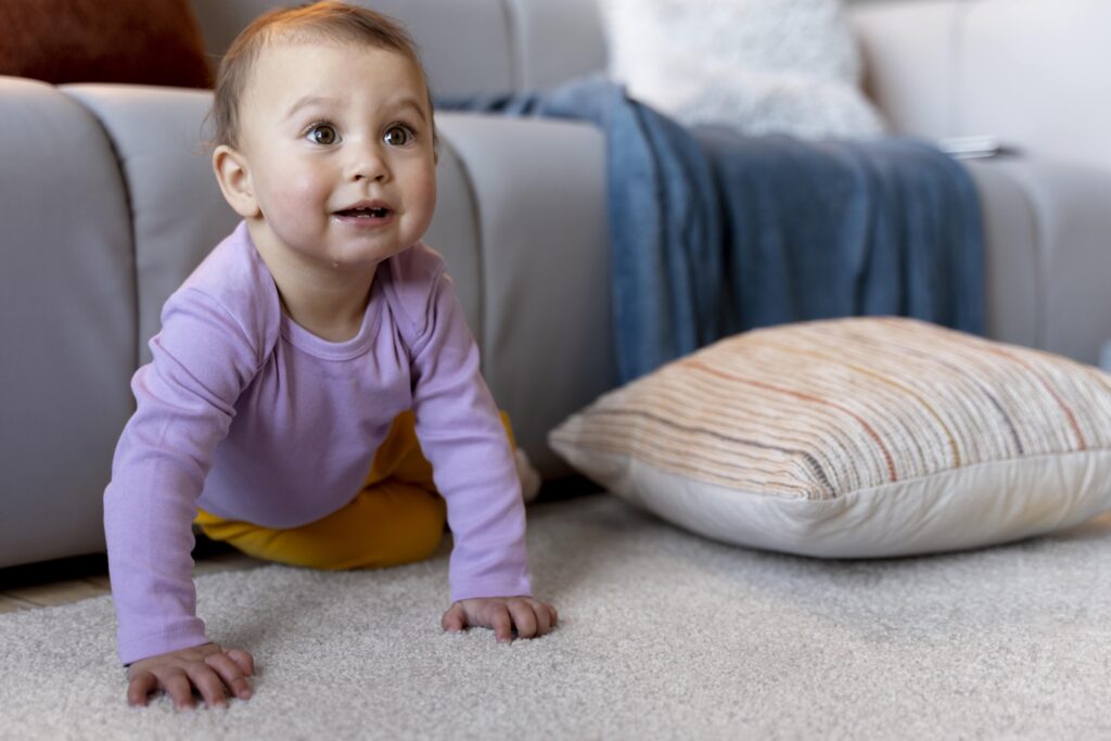 Baby krabbelt auf dem Boden vor einer Couch.